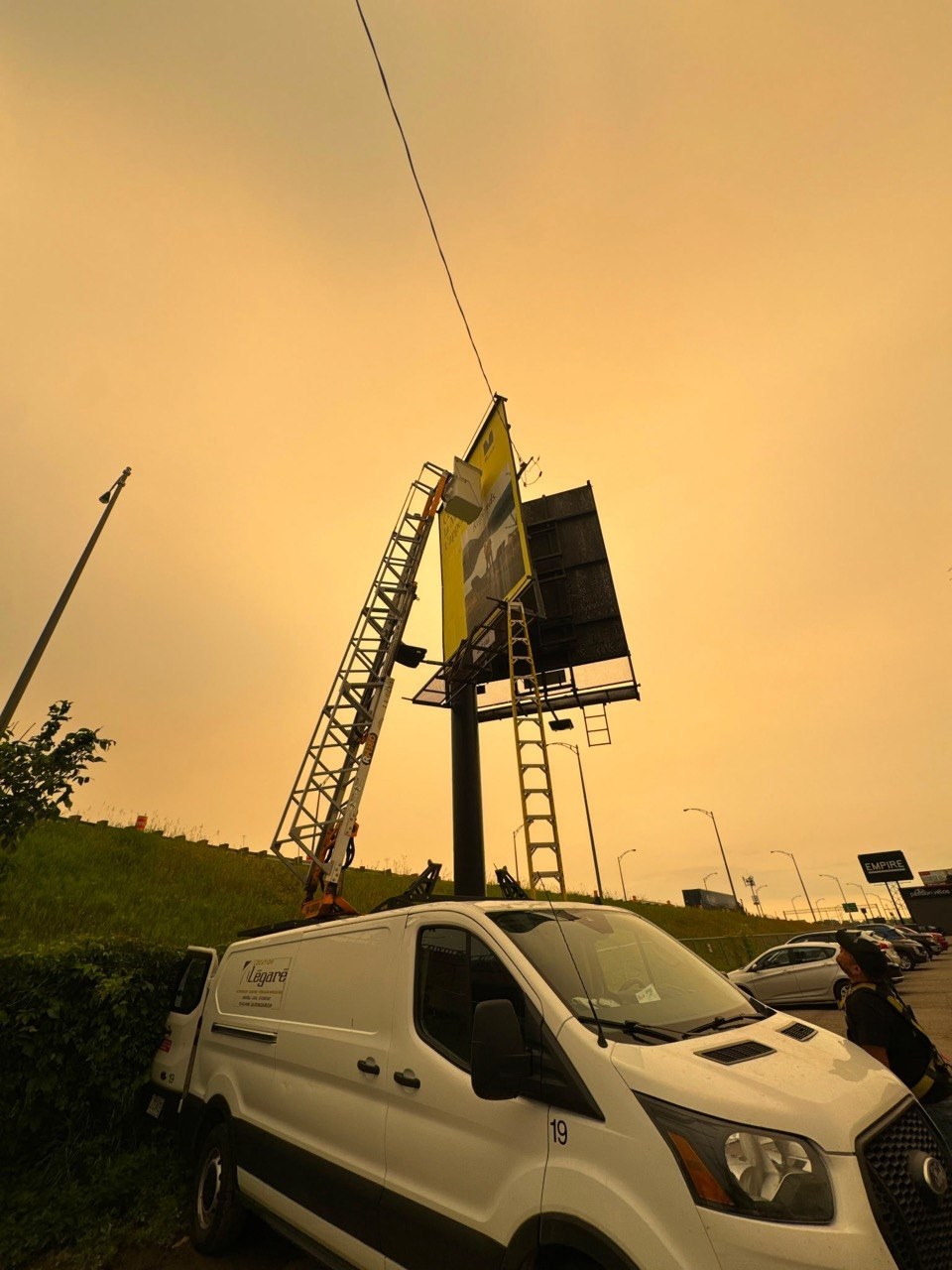 Grue et véhicule de l’équipe sur un chantier de panneau publicitaire